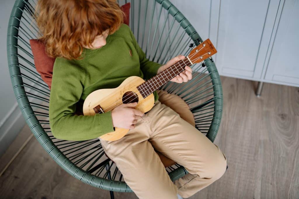 A child learning how to play a ukulele