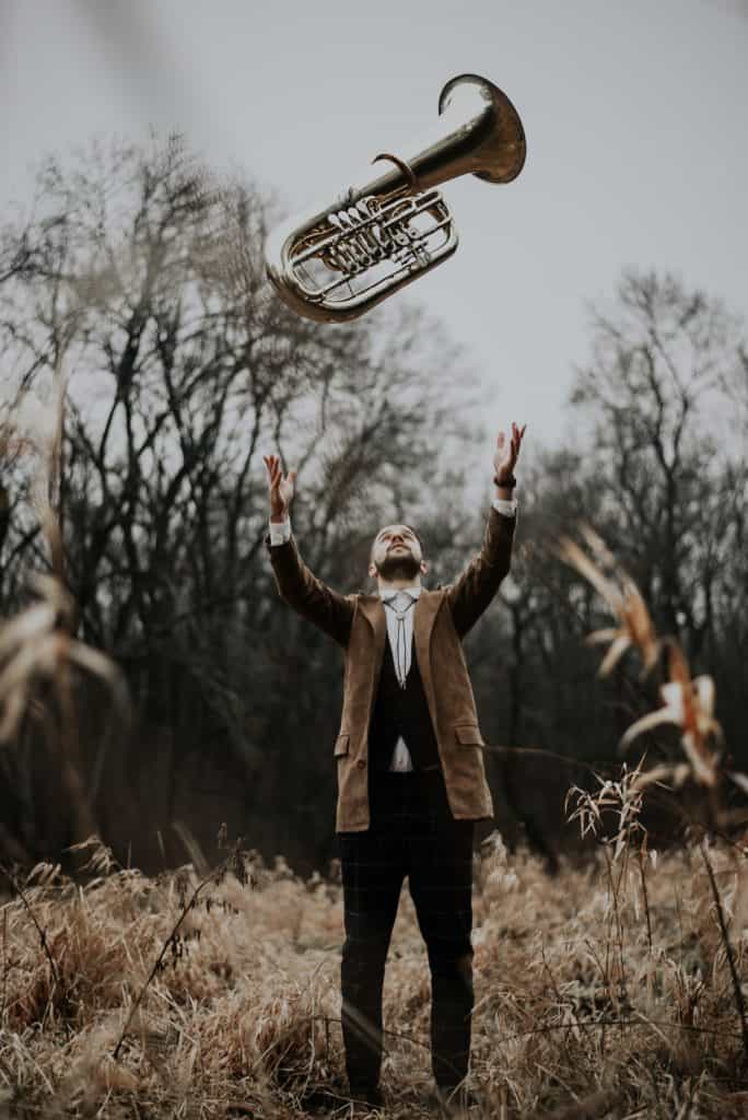 A man lifting a lightweight tuba in the air