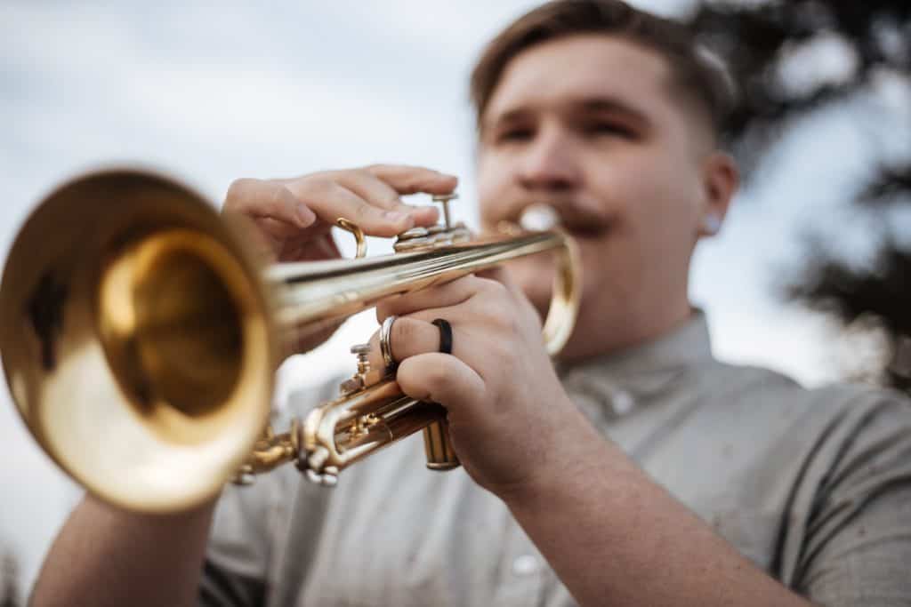 A man outdoor playing a bugle