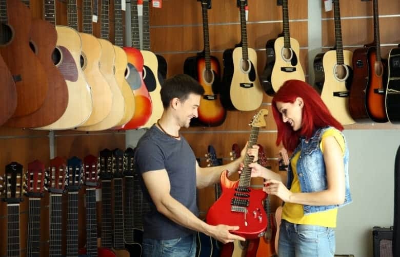 A store employee aids the customer in selecting a guitar