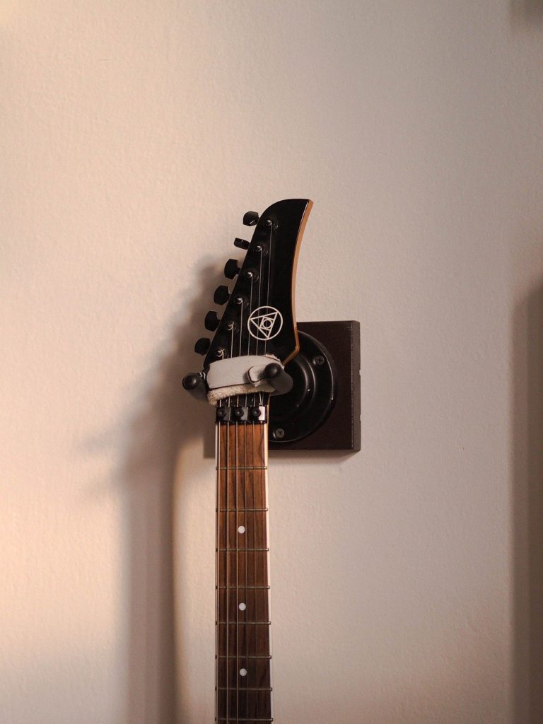 An electric guitar is hung from a guitar hanger.