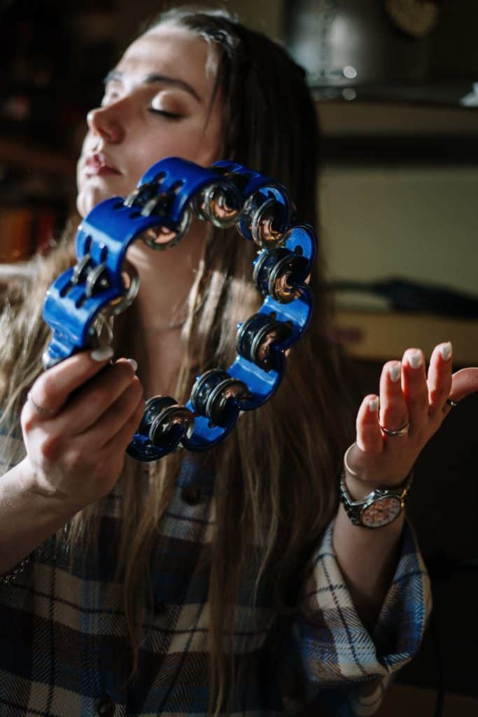 A woman playing a blue tambourine.