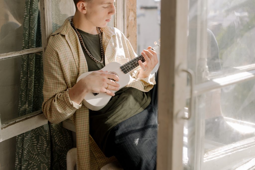 A man is tuning his ukulele.