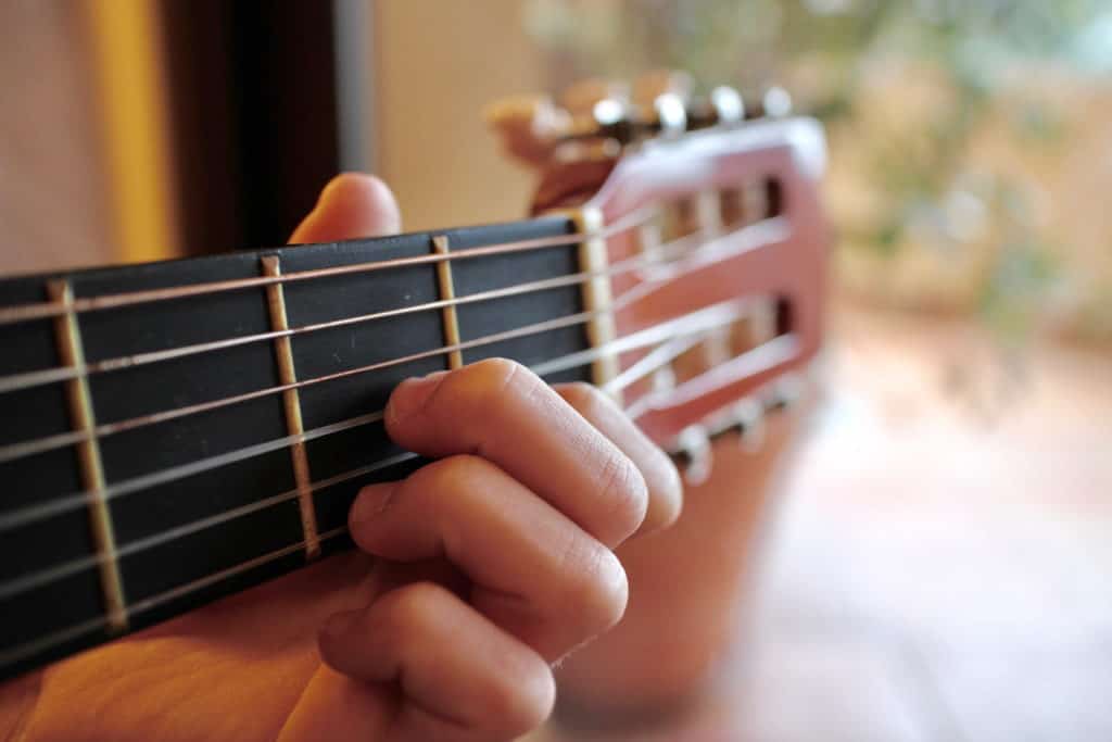 Small fingers pressing the strings of the guitar