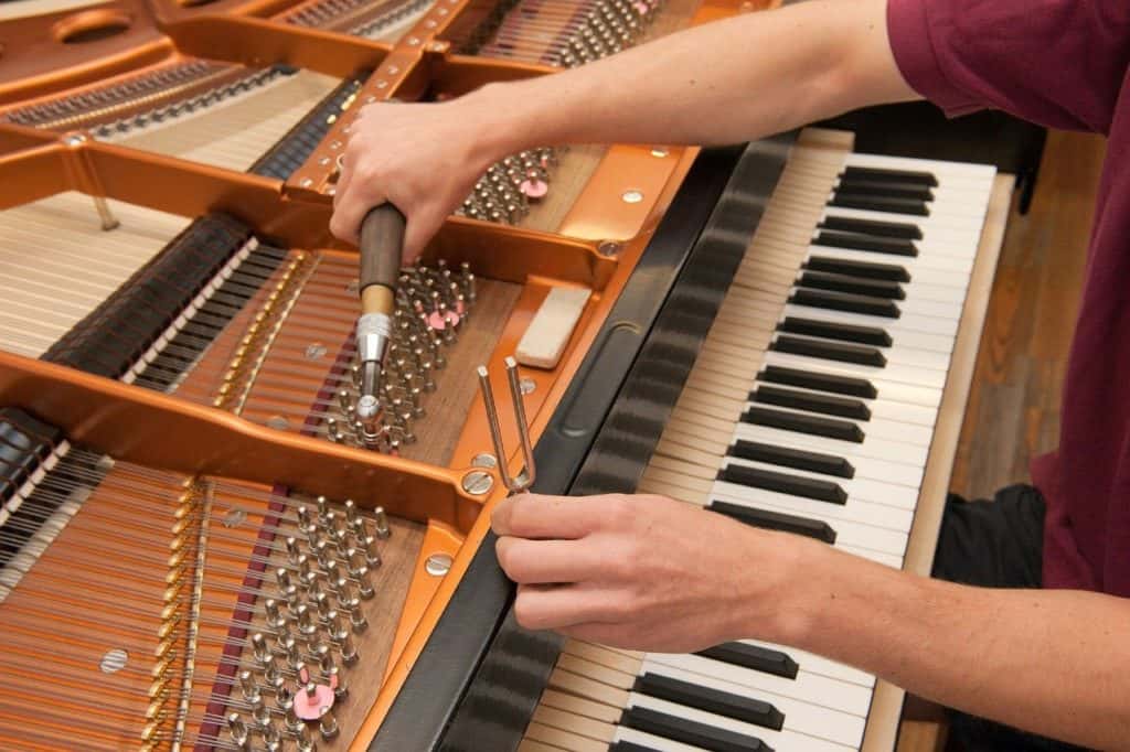 A close up of a man tuning a piano