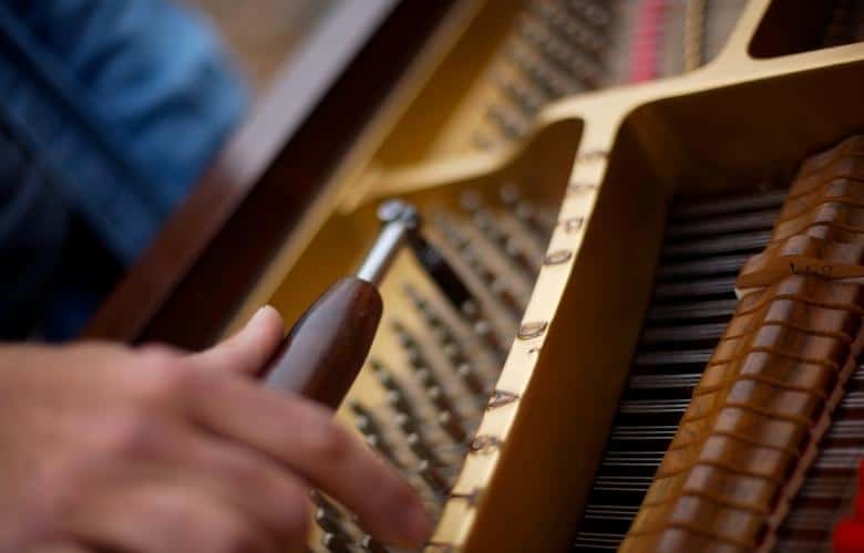 A piano tuner holding a tuning tool