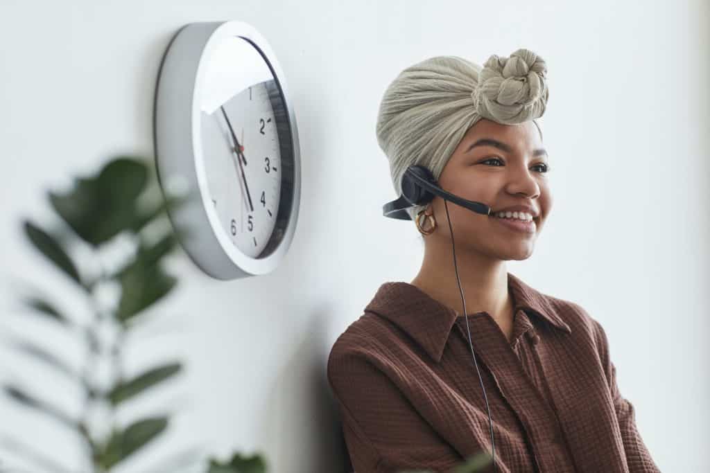 A woman wearing a headset with a big smile before she sings for a podcast