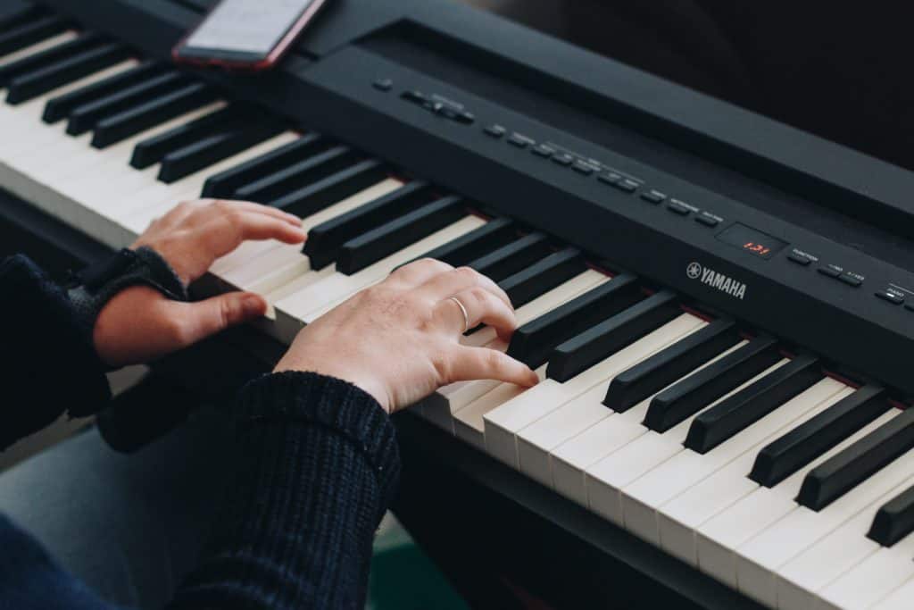 A close up of hands playing portable yamaha keyboard