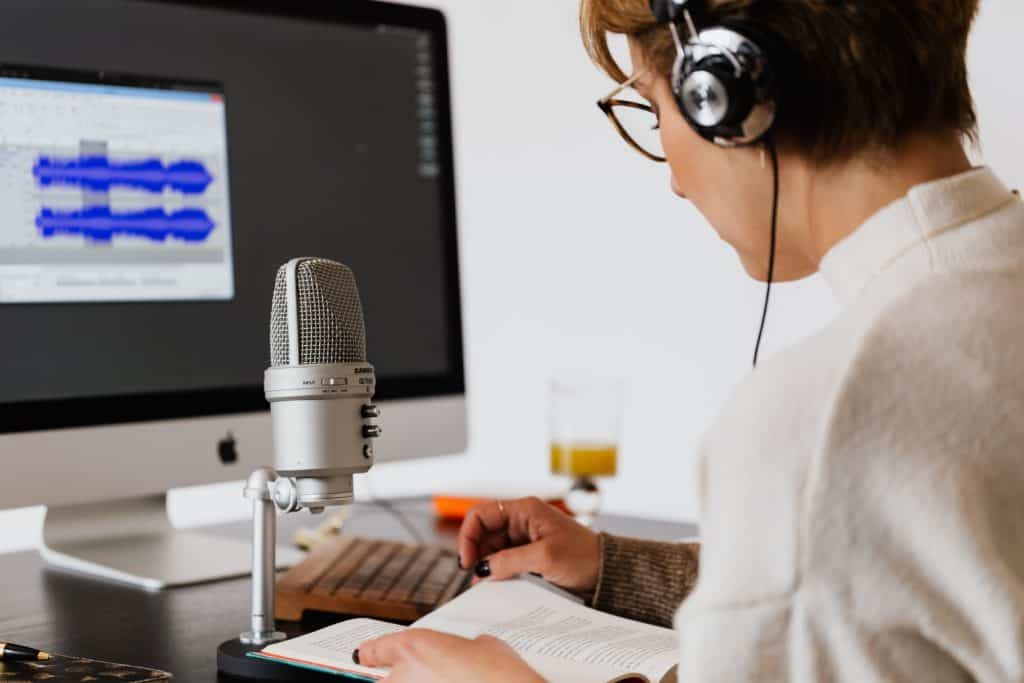 A woman uses a silver condenser microphone to stream her podcast.