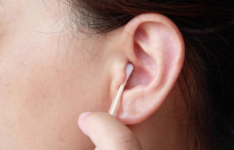 Woman holding cotton swab and cleaning ear