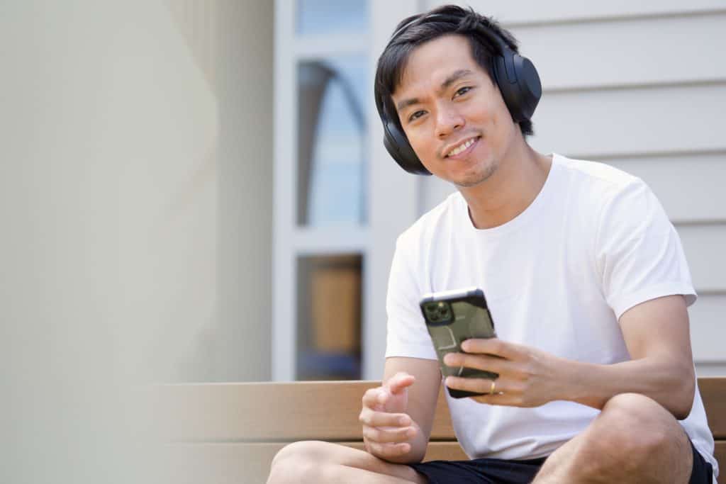 A man wearing a wireless bluetooth earphones while listening to music