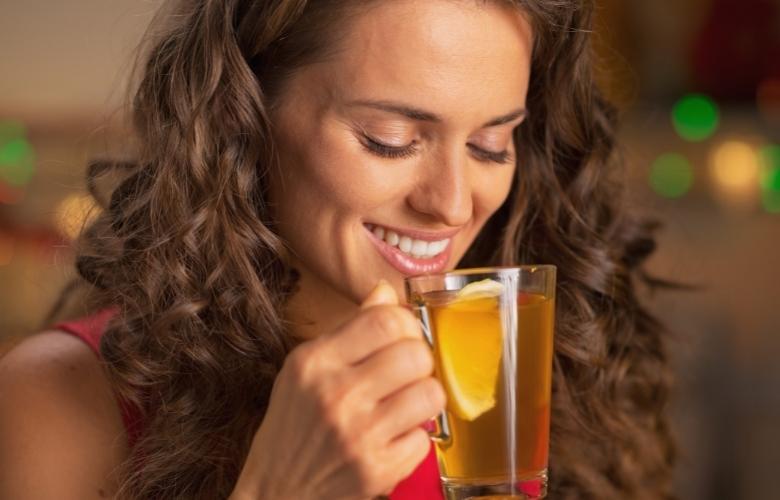 A woman drinking ginger tea with lemon